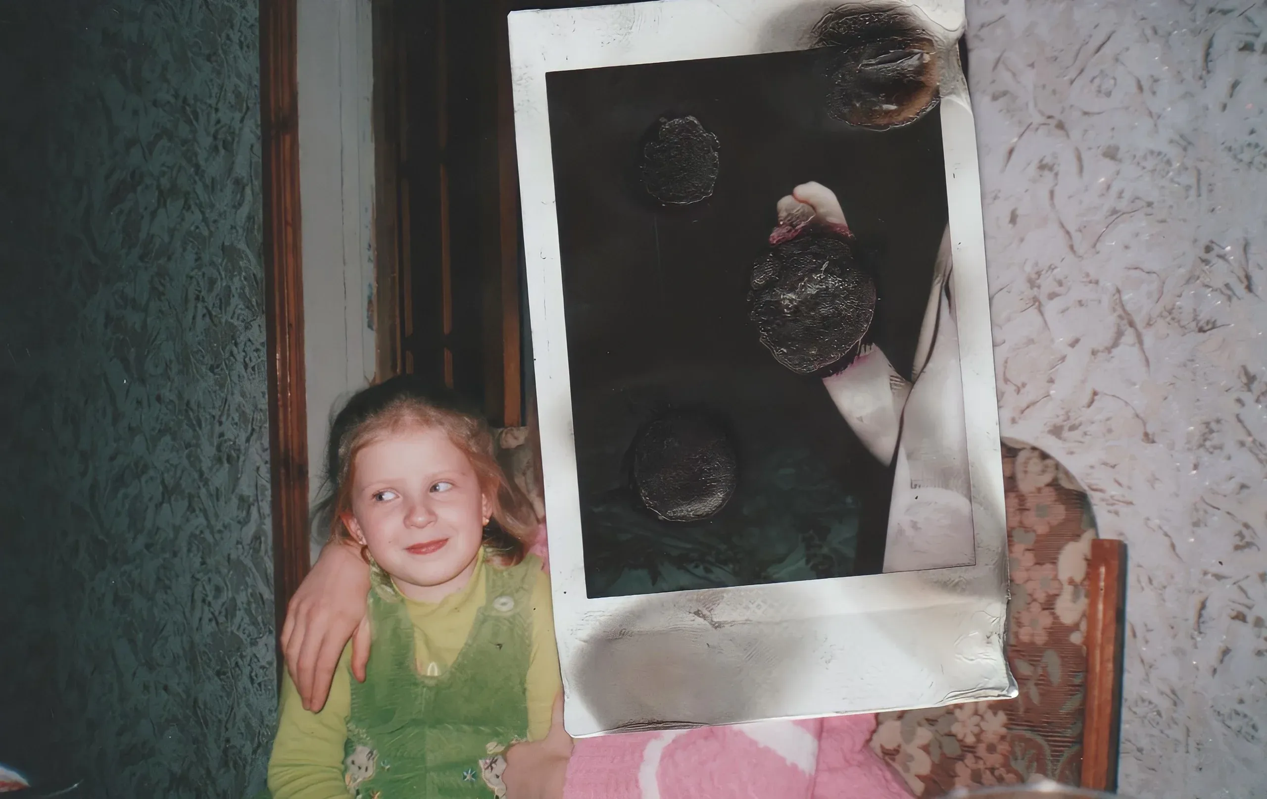 A child in a green shirt beside a burnt polaroid
