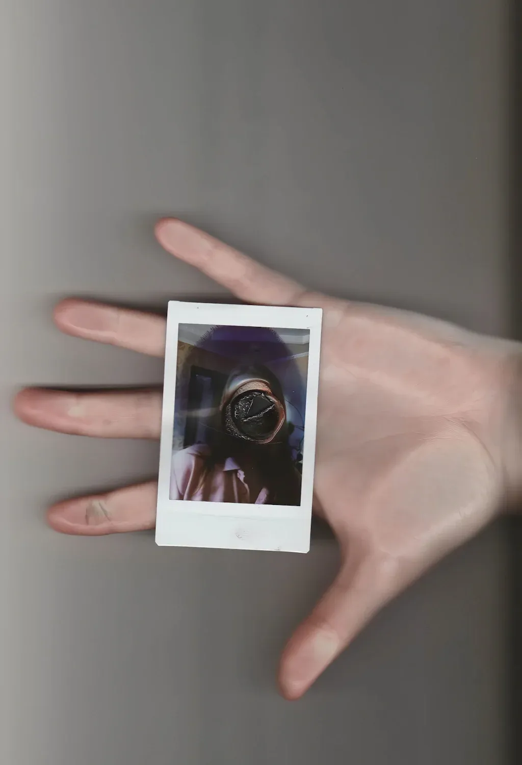 A burnt polaroid held in an open hand