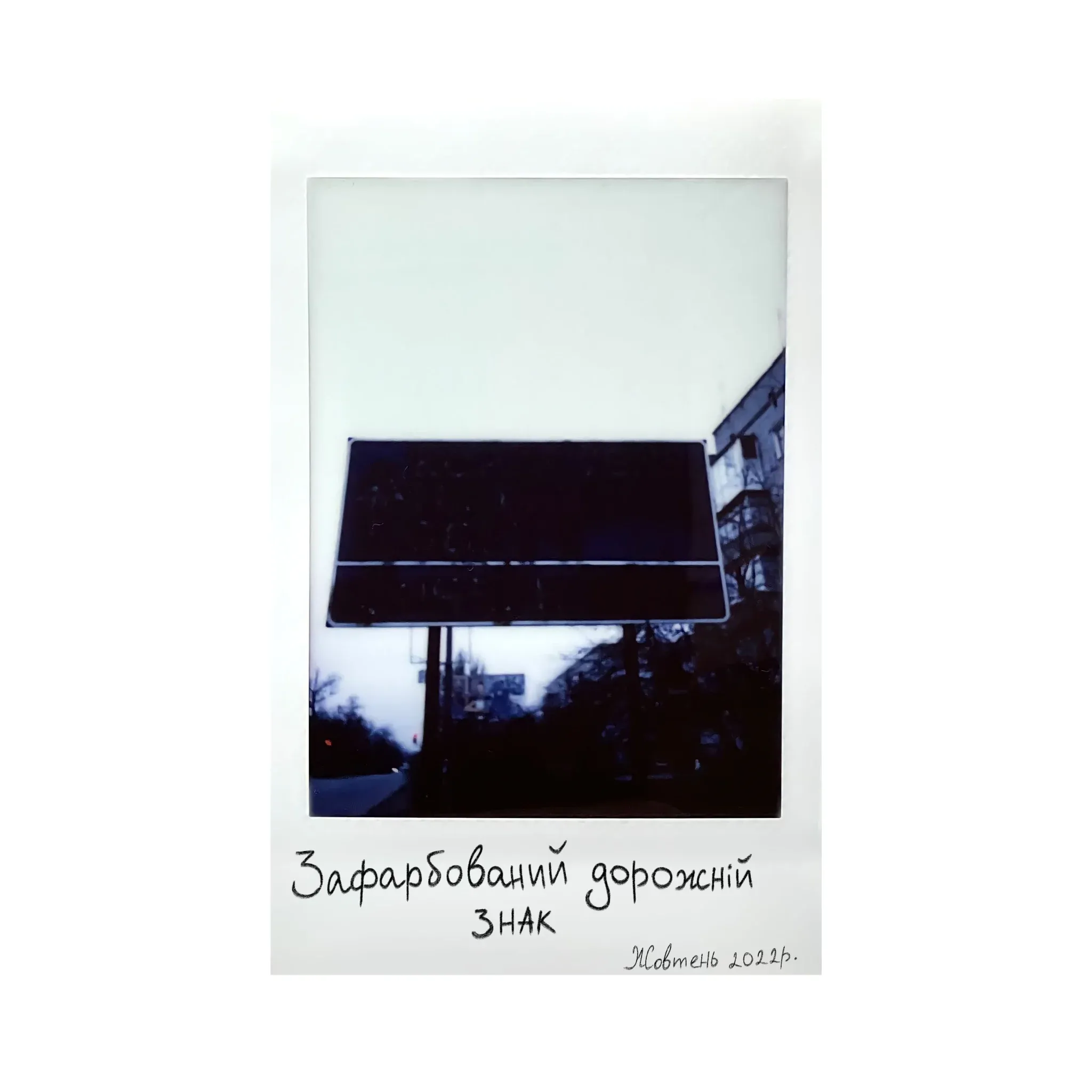 Polaroid of a road sign painted over in black