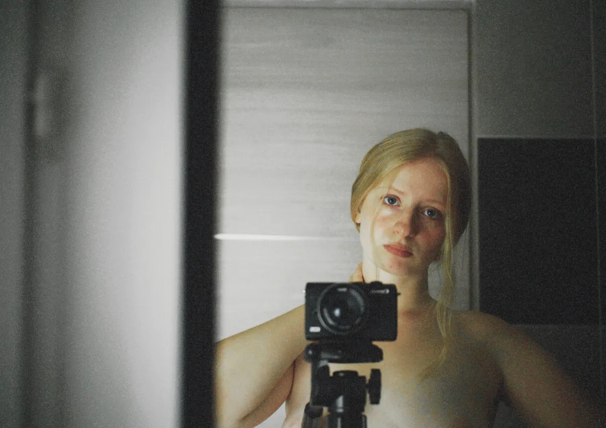 Self-portrait of the artist behind a camera on a tripod