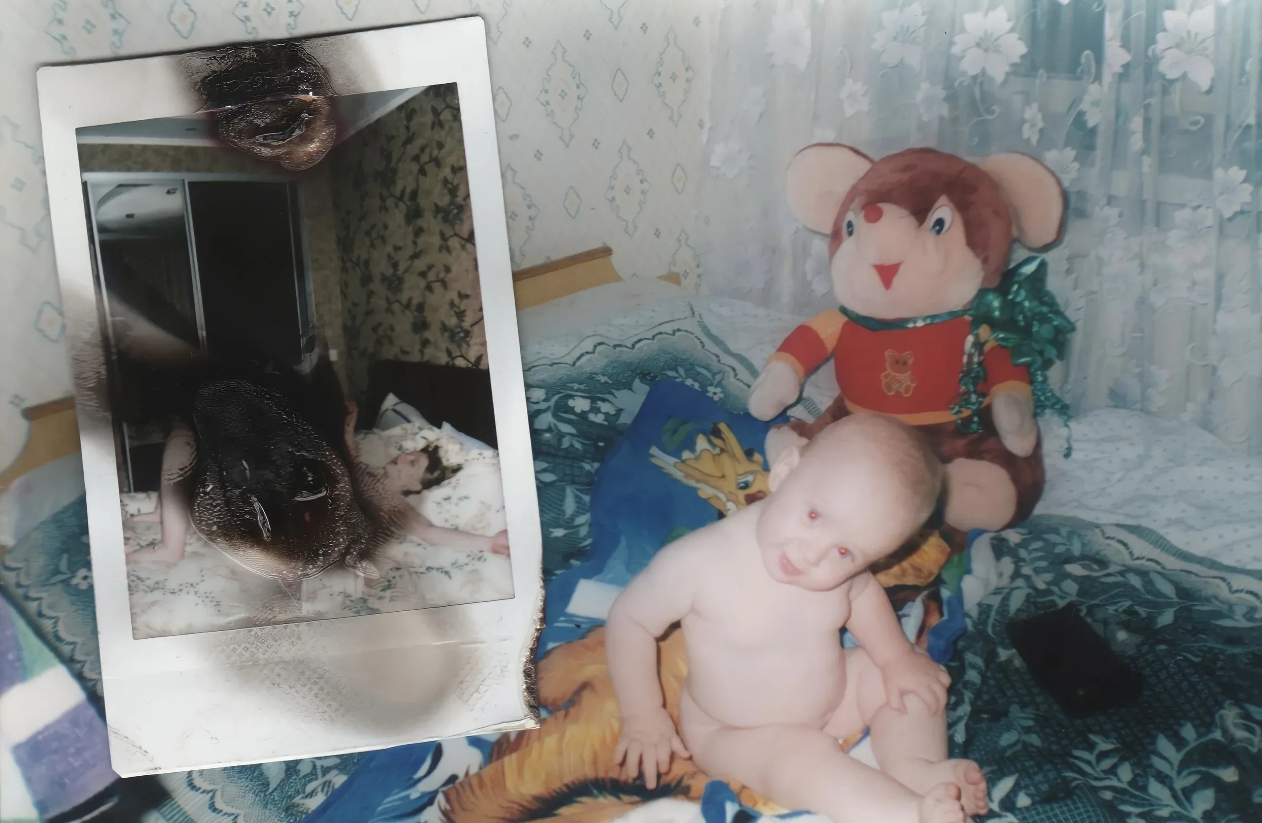 A baby with a toy mouse, with a burnt polaroid